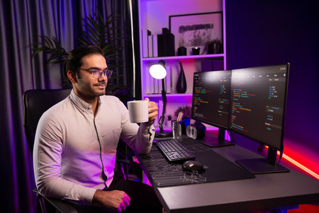 Smart IT developer drinking coffee cup while working in software development coding on pc screen,...
