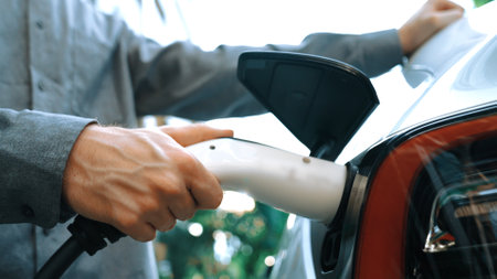 Young man recharge EV electric car in green sustainable city outdoor summer garden as lifestyle of young people in urban sustainability green clean rechargeable energy of electric vehicle innardsの写真素材