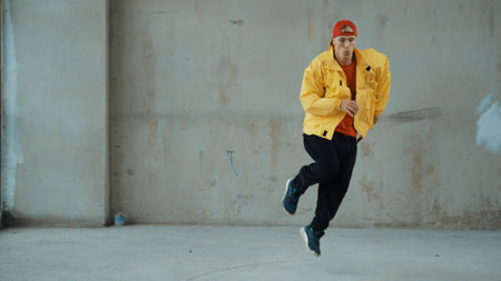 Caucasian hipster shows or practicing footstep at street, urban city. Motion shot of young stylish break dancer moving and stretch arm and leg. Outdoor sport 2024. Gray background. Endeavor.の写真素材
