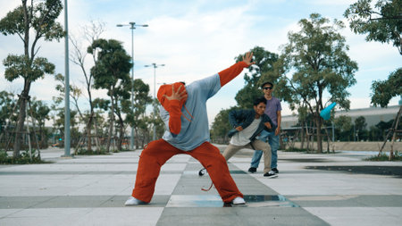 Attractive hipster doing b-boy dancing with multicultural friend. Professional handsome break dancer doing freeze pose while enjoy b-boy dancing. Modern lifestyle. Outdoor sport 2024. Sprightly.の写真素材