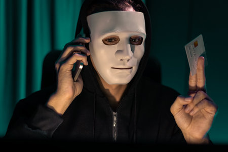 White criminal anonymous mask calling to credit card owner to threaten ransom with privacy information all database, making password encryption by programming hack trying to make insecure. Pecuniary.の写真素材