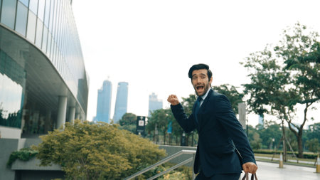 Dancing business man walking and hold bag while dancing at park. Happy funny project manager moving body to music while going to work. Happy man getting promotion, receive good news. Exultant.の写真素材