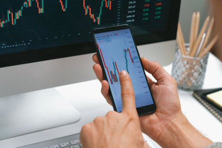 Smart stock investors pointing on screen with smartphone for market stock exchange along with laptop...
