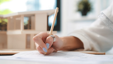 Closeup image of young beautiful caucasian architect engineer hand write mistake points on blueprint...
