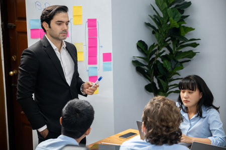 Productive boss or manager demonstrate strong commitment to effective business management on meeting room with diverse race employee, plan and discuss business marketing on meeting table. Meticulousの写真素材