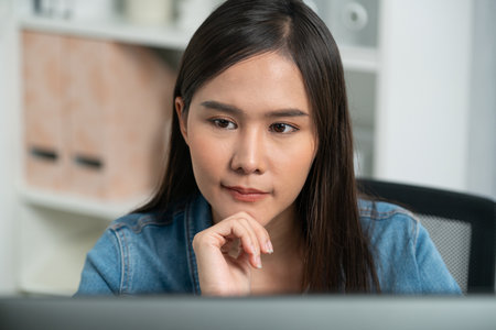 Working young beautiful asian creative manager focusing on pc, creating with new website design on new social media online channel planning with blue jeans shirt at modern home office. Stratagem.の写真素材
