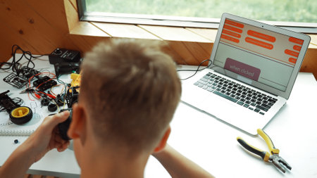 Top view of happy student study car model construction at table with electronic equipment and laptop display coding program screen scatter around at STEM classroom. Creative education. Edification.の写真素材