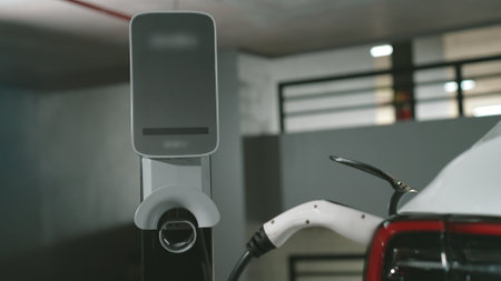 EV electric car recharge at shopping center multistorey indoor parking lot charging in downtown city showing urban sustainability green clean rechargeable energy lifestyle of electric vehicle innardsの写真素材