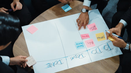 Top view of business people hands making scrum task board to manage workflow in workplace. Diverse...
