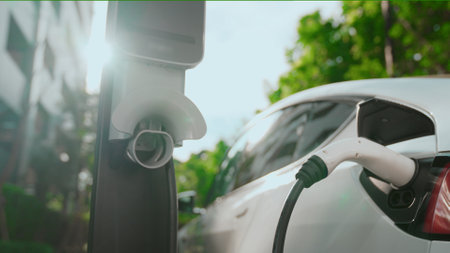 EV electric car charging in green sustainable city outdoor garden in summer. Urban sustainability...