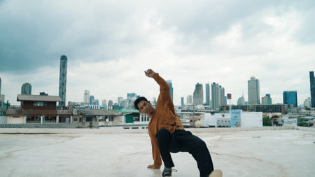 Motion shot of B-boy dance performance by professional street dancer at rooftop with sky scrapper,...
