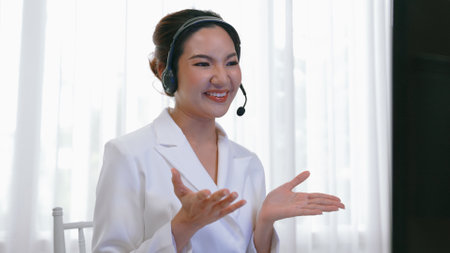 Businesswoman wearing vivancy headset working in office to support remote customer or colleague. Call center, telemarketing, customer support agent provide service on telephone video conference callの写真素材