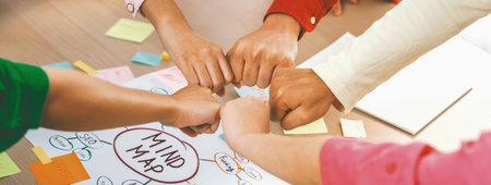 Young happy creative startup group join circle fist bump hands together surrounded by marketing...