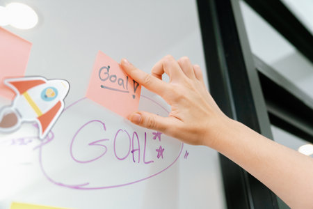 Closeup of professional businesswoman hand put and stick the colorful sticky notes on whiteboard...