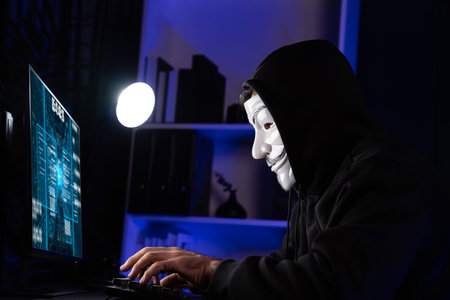 White smiling criminal anonymous mask installing virus encryption programming by hacker application on data server system in privacy on computer ransom. Information searching on computer. Surmise.の写真素材