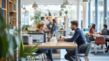 Blurred photo capturing the dynamic atmosphere of a modern open-plan office with people engaged in...