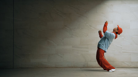 Handsome choreographer practice street dance in gray background. Young attractive b boy dancer perform while wearing stylish cloth. Feeling of lively step. Copy space. Outdoor sport 2024. Sprightly.の写真素材