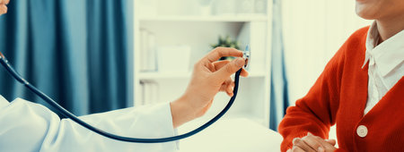 Patient attend doctors appointment at clinic or hospital office. Doctor examining and diagnosis symptoms while checking the patients pulse with stethoscope. Panorama Rigidの写真素材