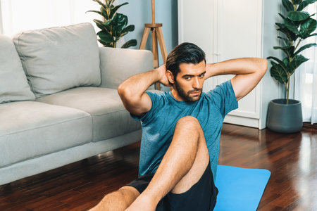 Athletic and sporty man doing crunch on fitness mat during home body workout exercise session for fit physique and healthy sport lifestyle at home. Gaiety home exercise workout training concept.の写真素材