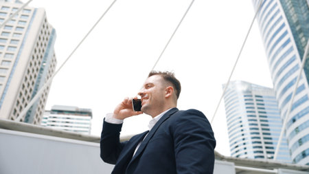 Smart caucasian businessman calling his colleague to plan financial strategy while standing at urban city. Project manager using his mobile phone to communicate with marketing team. Lifestyle. Urbane.の写真素材