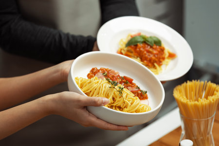 Close up of hand couple chef influencers completely cooked spaghetti with meat topped with tomato sauce special dish on live chanel. Concept of serving healthy food at modern home studio. Postulate.の写真素材