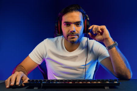 Smart gaming streamer looking at camera with trendy pose, passing the level of online game user on pc, using headset and mic for communicate with others at digital neon light studio room. Surmise.の写真素材