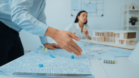 Skilled caucasian interior designer working with house model while discussing with asian architect...