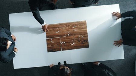 Top view of business people putting jigsaw together at meeting room. Professional marketing team standing at table while gathering puzzle piece. Show unity, cooperation and team working. Directorate.の写真素材