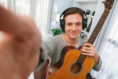 Host channel in smart singer looking camera with selfie pose of holding guitar, broadcasting on...