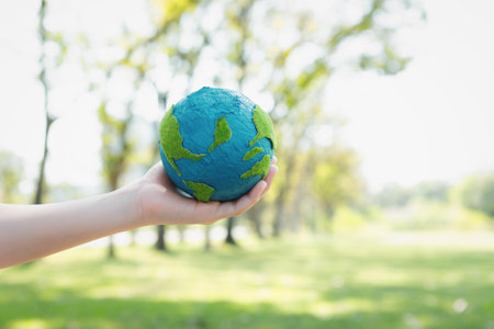 Young boys hand holding planet Earth globe at natural park background as Earth day to save this planet with ESG principle and environment friendly energy for brighter future. Gyreの写真素材