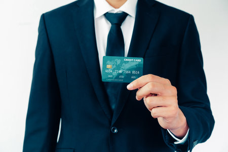 Portrait of businessman holding a credit card showing front view to the camera in close up view. Online shopping business and cashless payment concept. udsの写真素材