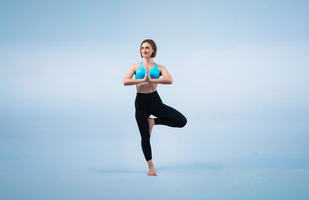 Full body length gaiety shot athletic and sporty woman doing healthy and meditative yoga exercise workout posture on isolated background. Healthy active and body care lifestyleの写真素材