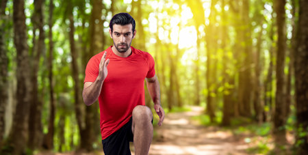 Athletic and sporty man running posture at outdoor green forest exercise session for fit physique and healthy outdoor sport lifestyle. Gaiety green foliage tree exercise workout training.の写真素材