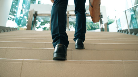 Closeup of business man leg go up the stairs. Successful man going up the stairs while explore a new thing. Traveling, getting a promotion, finding a new job, increasing skill. Back view. Exultant.の写真素材