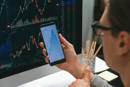 Smart stock investors pointing on screen with smartphone for market stock exchange along with laptop...