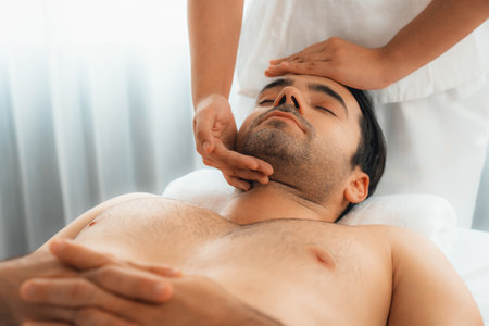 Caucasian man enjoying relaxing anti-stress head massage and pampering facial beauty skin recreation leisure in dayspa modern light ambient at luxury resort or hotel spa salon. Quiescentの写真素材
