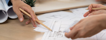 Cropped image of professional architect engineer hand pointing at blueprint by using pencil while...