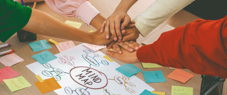 A group of business people putting their hands together at meeting room on table with mind map...