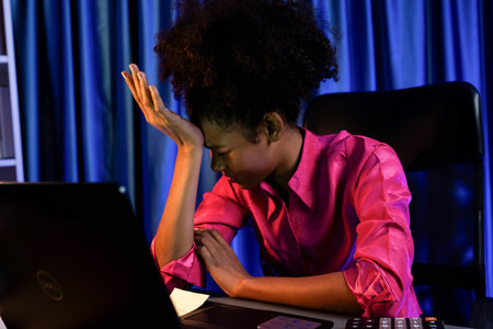 Working African businesswoman suffering from headache with online job, sitting at home office,...