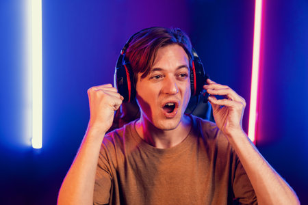Host channel of gaming smart streamer playing online game to be winner, wearing headphone with viewers live steaming on media social online for selected team competition at neon light room. Pecuniary.の写真素材