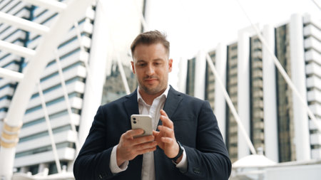 Caucasian business man checking mobile phone and looking report sales from marketing team while standing at urban city. Skilled manager working on mobile phone and looking at data analysis. Urbane.の写真素材