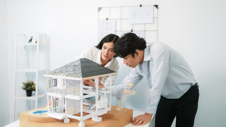 Closeup of young professional skilled architect engineer team focusing on checking the house model structure at modern office. Creative professional design and teamwork concept. Immaculate.の写真素材