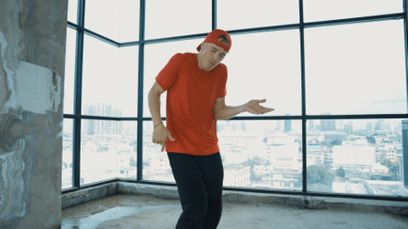 Motion shot of energetic caucasian hipster dance together near window sky scraper. Stylish energetic dancer pose while looking at camera. Outdoor sport 2024. Freestyle dancing. Endeavor.の写真素材