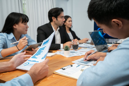 Diverse group of business analyst team analyzing financial data report paper on office table. Chart and graph dashboard by business intelligence analysis for strategic marketing planning Habilimentの写真素材