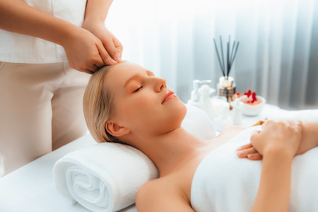 Caucasian woman enjoying relaxing anti-stress head massage and pampering facial beauty skin recreation leisure in dayspa modern light ambient at luxury resort or hotel spa salon. Quiescentの写真素材