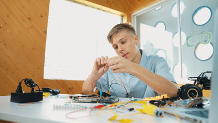 Smart happy boy inspect or learning to use electronic tool to fix car model. Highschool student studying about electric equipment to repair robotic machines while sitting at STEM class. Edification.の写真素材
