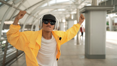 Closeup of skilled hipster listen music from headphone while moving hand. Professional break dancer perform freestyle footstep while walking and looking at camera. Outdoor sport 2024. Sprightly.の写真素材