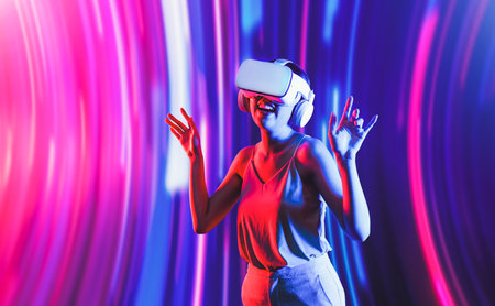 Smart female standing surrounded by neon light wearing VR headset connecting metaverse, future cyberspace community technology. Elegant woman enjoy dancing wavering body and sing song. Hallucination.の写真素材