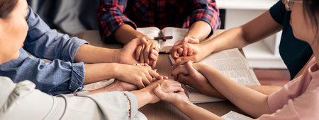 Cropped image of diversity people hand praying together at wooden church on bible book while hold hand together with believe. Concept of hope, religion, faith, god blessing concept. Burgeoning.の写真素材