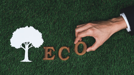 Hand arrange wooden alphabet in ecological awareness campaign with ECO icon design on biophilia green grass background to promote environmental protection for greener and sustainable future. Gyreの写真素材